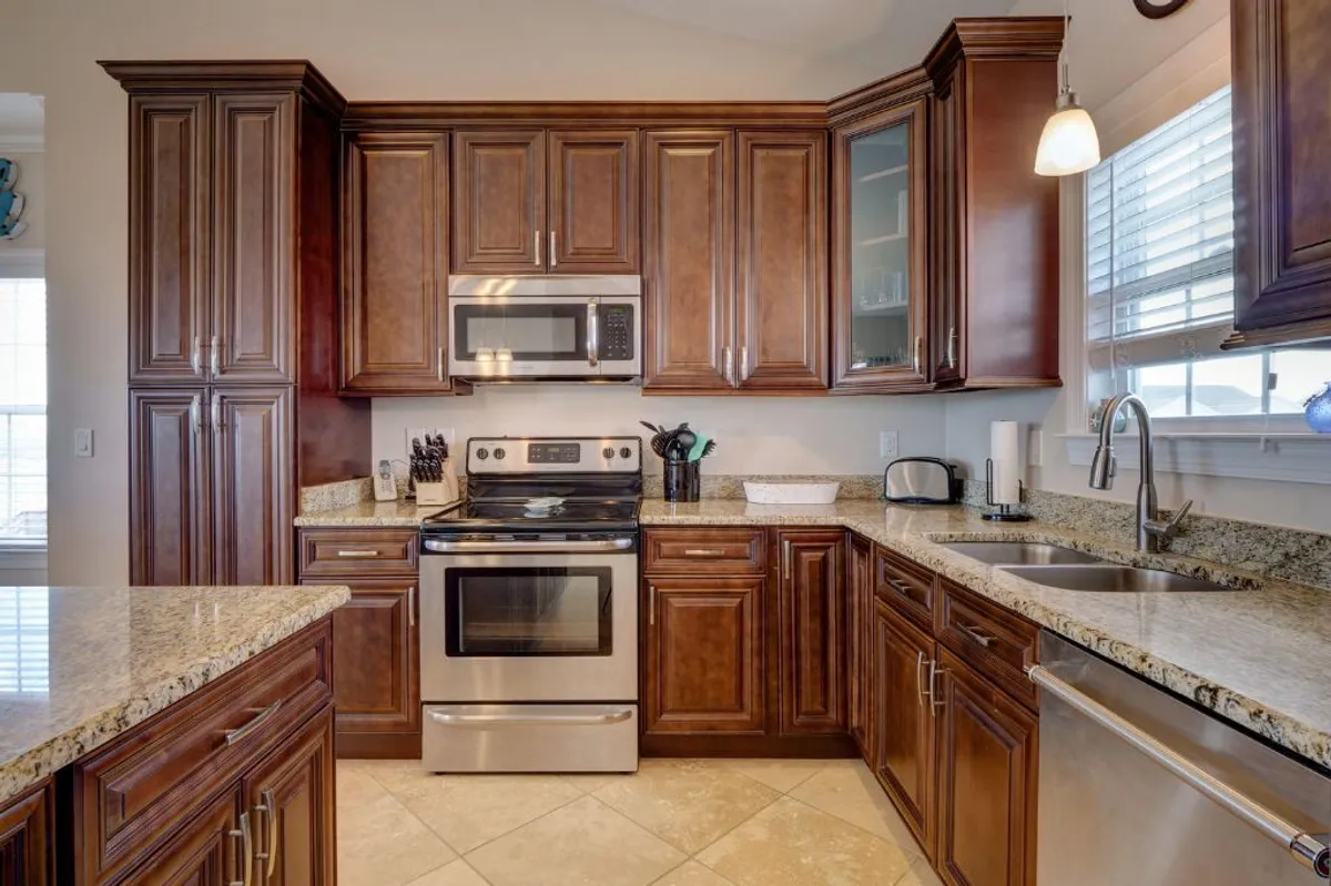 A modern kitchen with granite countertops, dark wood cabinetry, and stainless steel appliances. The layout is open and welcoming, ideal for preparing group snacks or mixing up beachside cocktails.